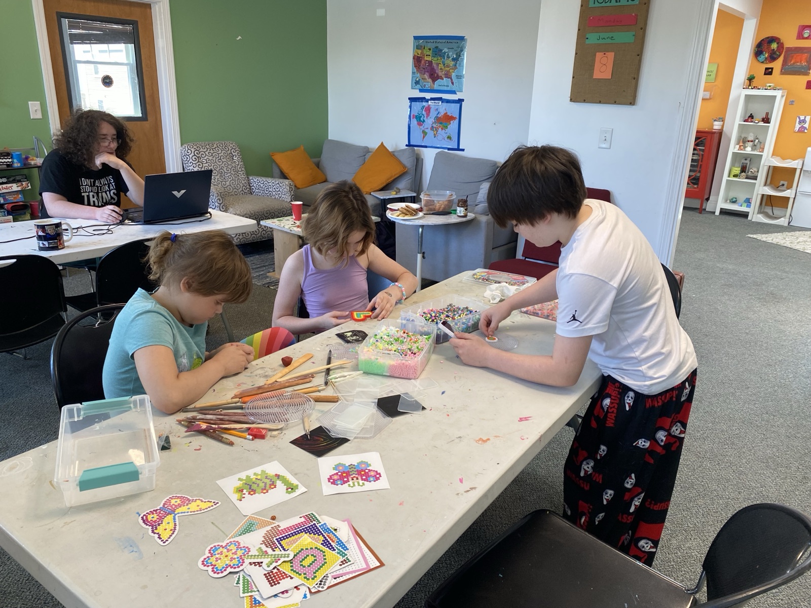 Kids collaborating on bead art at a craft table