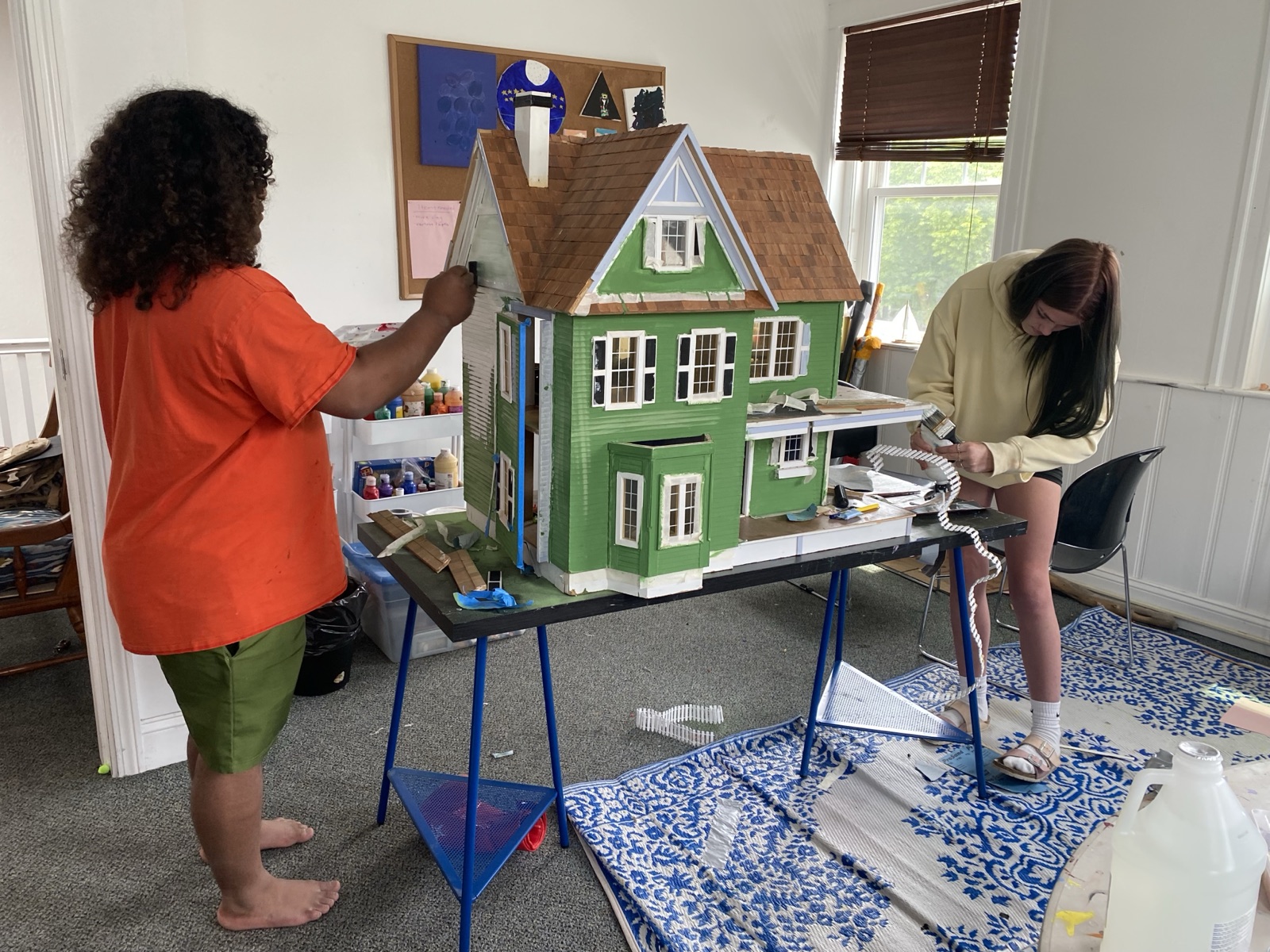 Two students building and painting a detailed model house