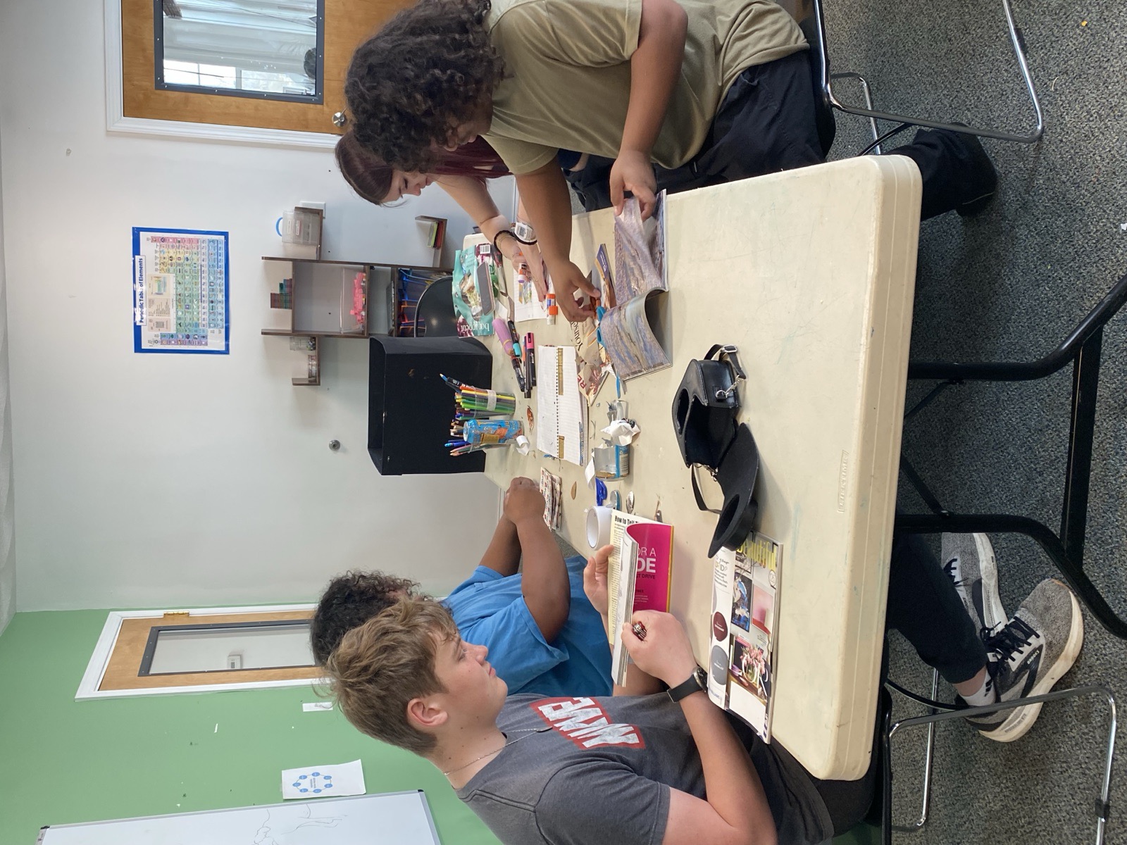 Students collaborating on a scrapbook project at a table